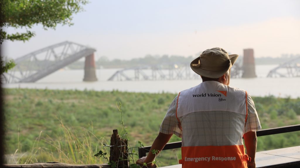 World Vision medewerker kijkt naar een brug die ingestort is door de verwoestende aardbeving